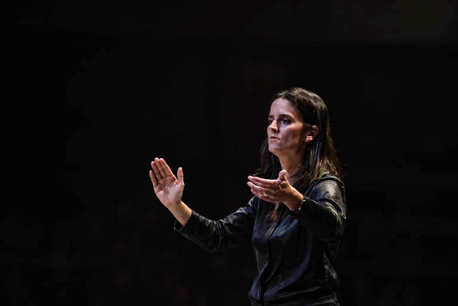 Romina Romay dirigeant un orchestre, les mains levées dans un geste musical